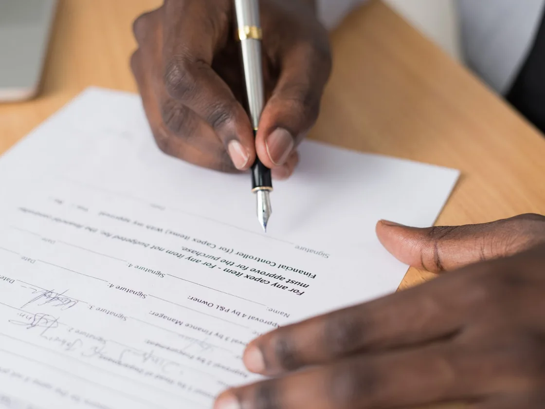 Hands signing estate paperwork at a table