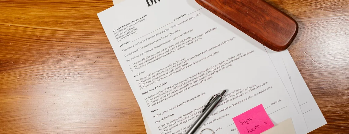 A Texas divorce petition on a desk with a pen, a wedding ring and a sign here note