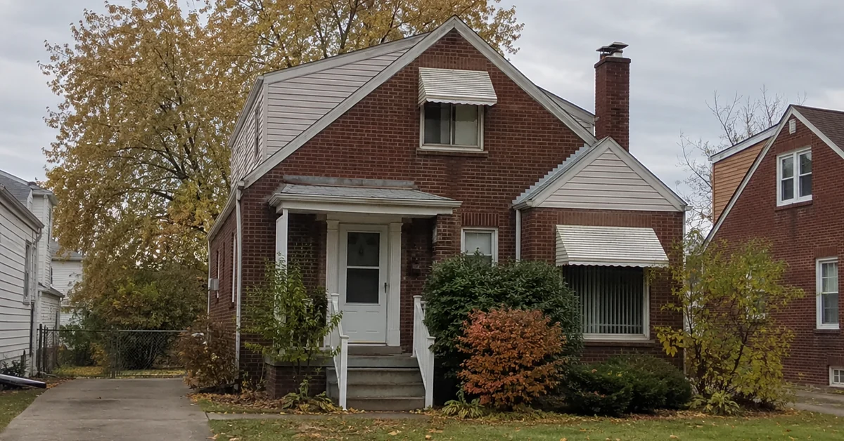 A modest older brick single-family house on a tree-lined Cleveland street, the kind of home often passed down through a family
