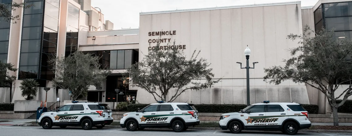 Three county sheriff patrol vehicles parked along the kerb outside a county courthouse building