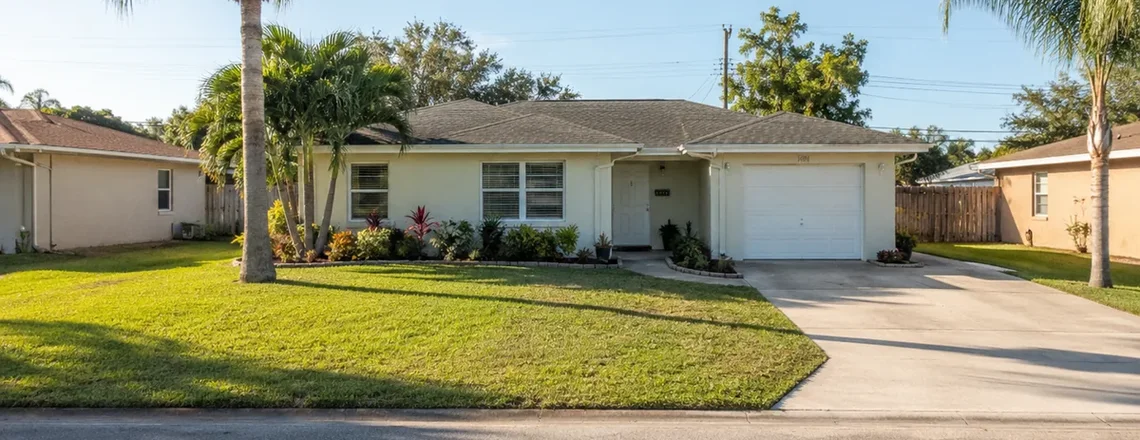 A modest single-story Florida house with palms on an ordinary Cape Coral street