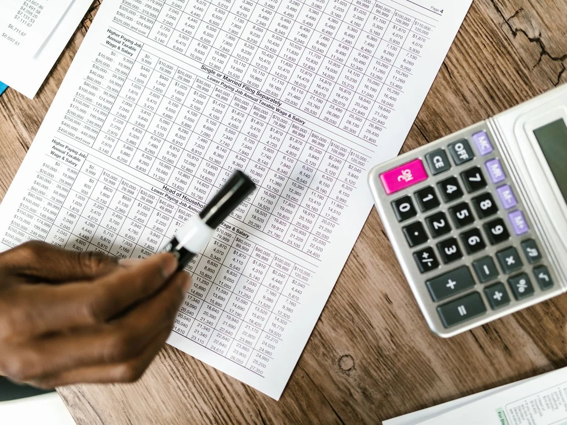 Tax paperwork and a calculator on a kitchen table while a homeowner works out the monthly cost of holding a house
