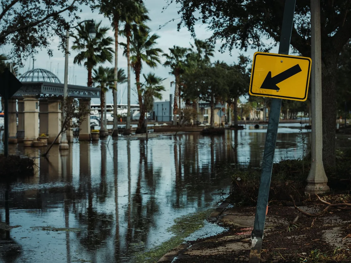 A flooded Florida street lined with palms and storm debris after heavy water, the history a Tampa seller now has to disclose in writing
