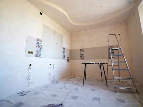 Renovation work underway inside an older Detroit house, drop cloths and tools in an empty room