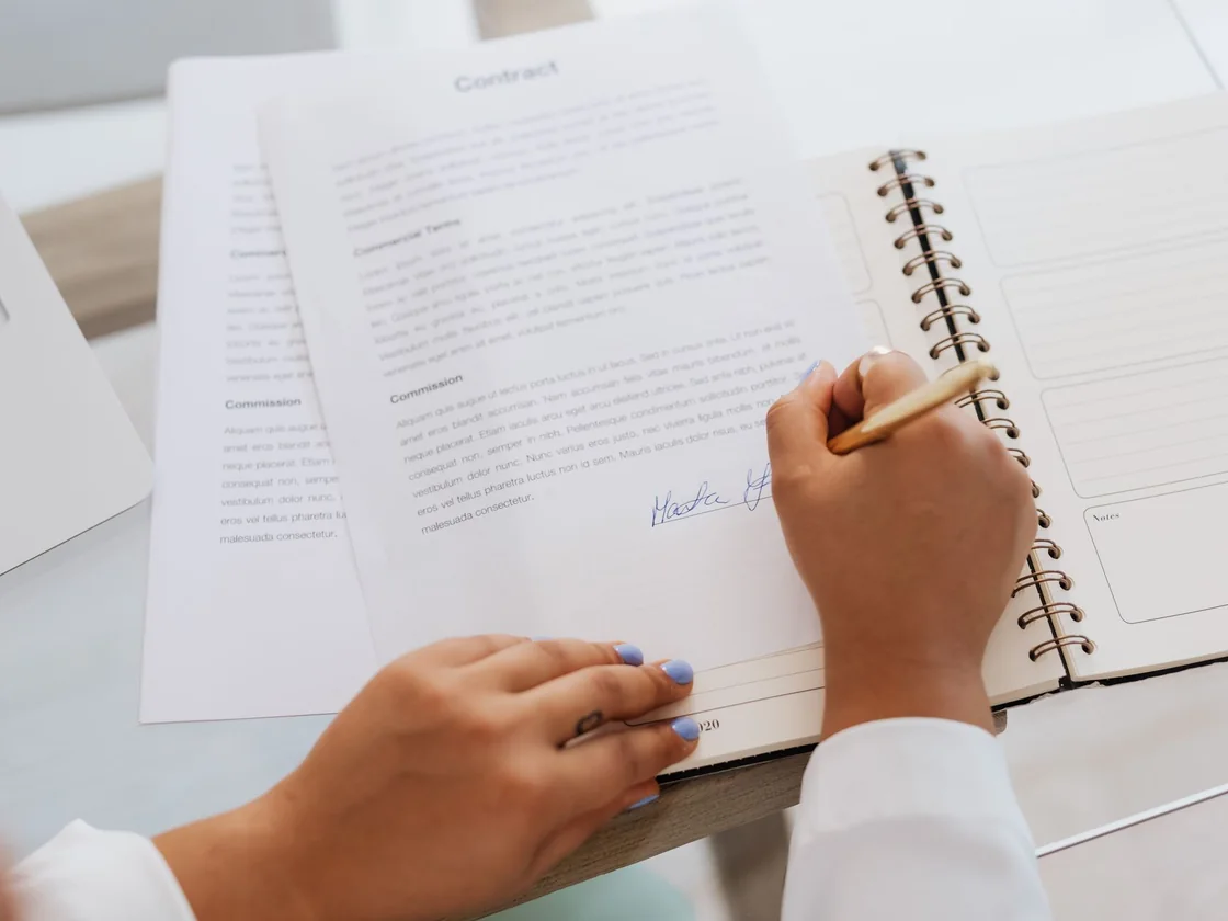 Hands signing a contract at a desk before selling a house during a Texas divorce