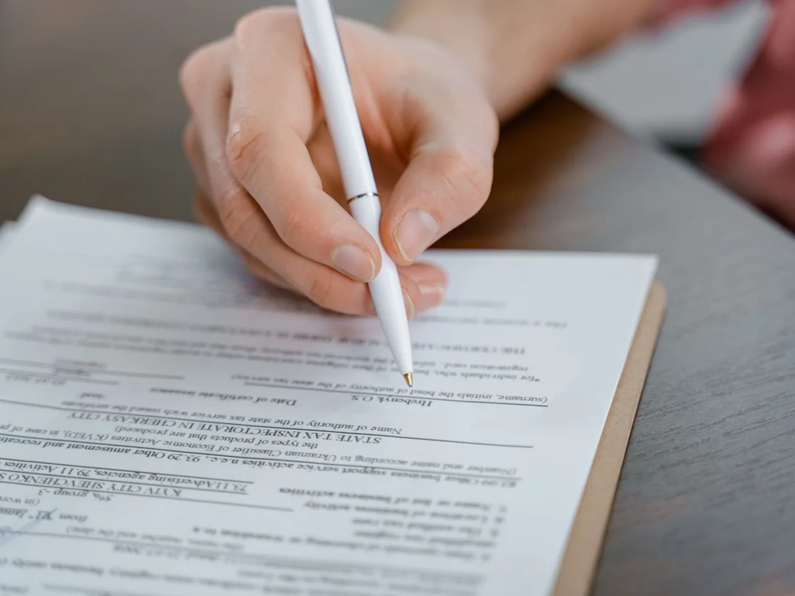 A hand signing paperwork at a table before selling a Florida house