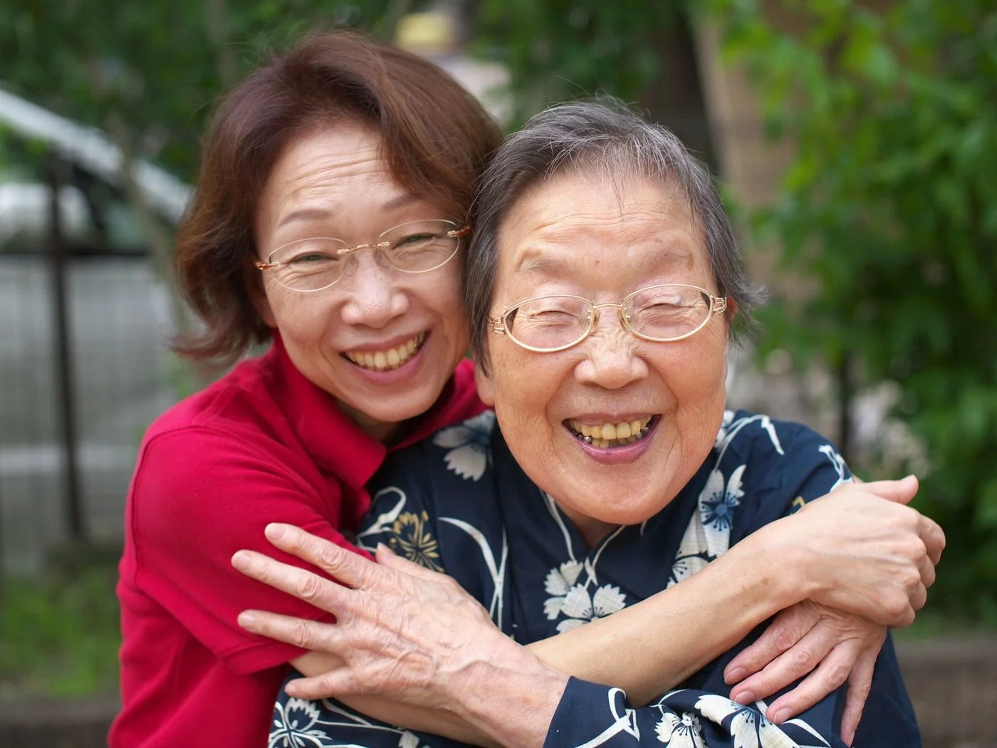 Adult daughter hugging her mother outside on a sunny day