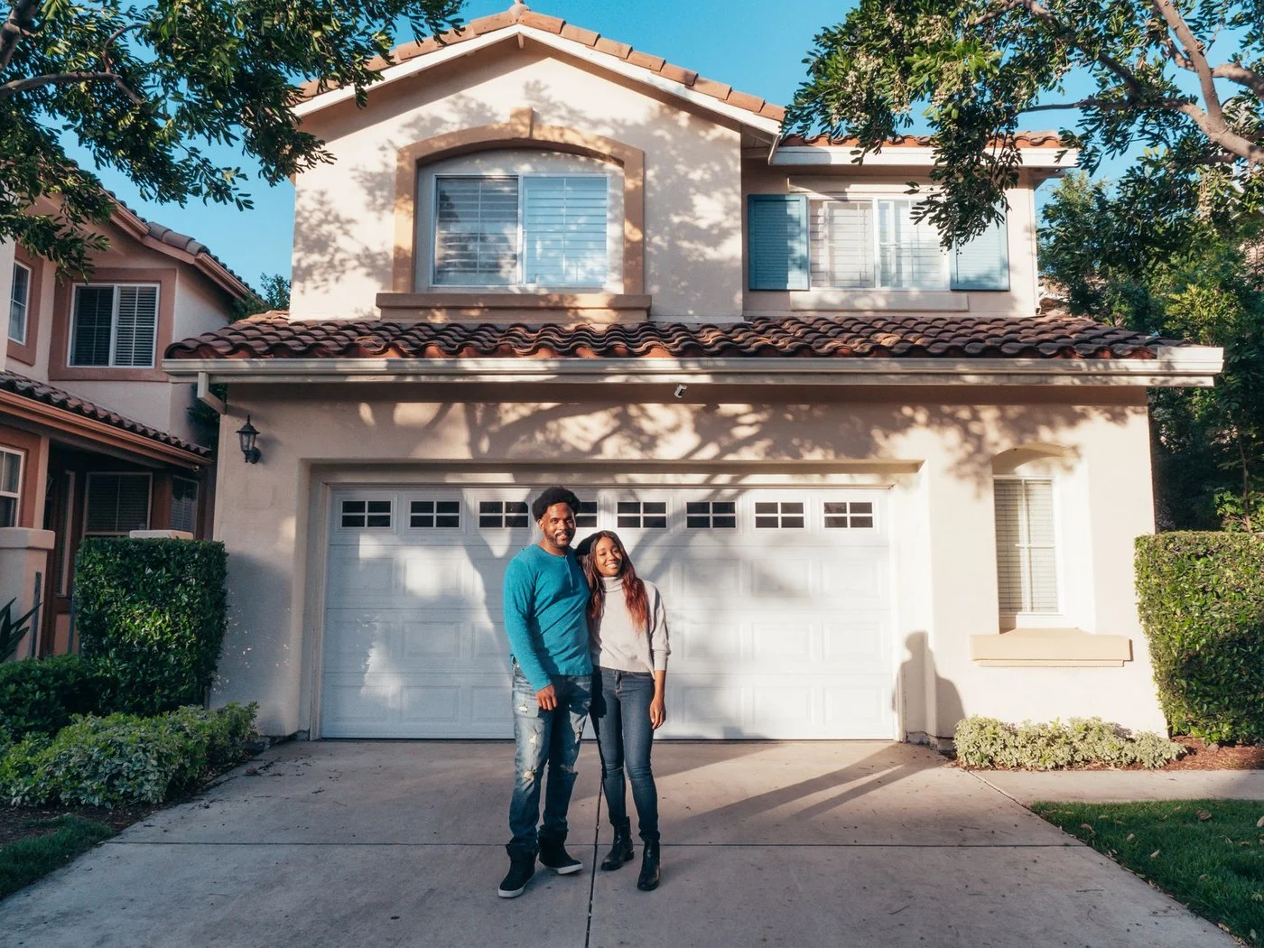 Happy couple standing in front of their house at sunset