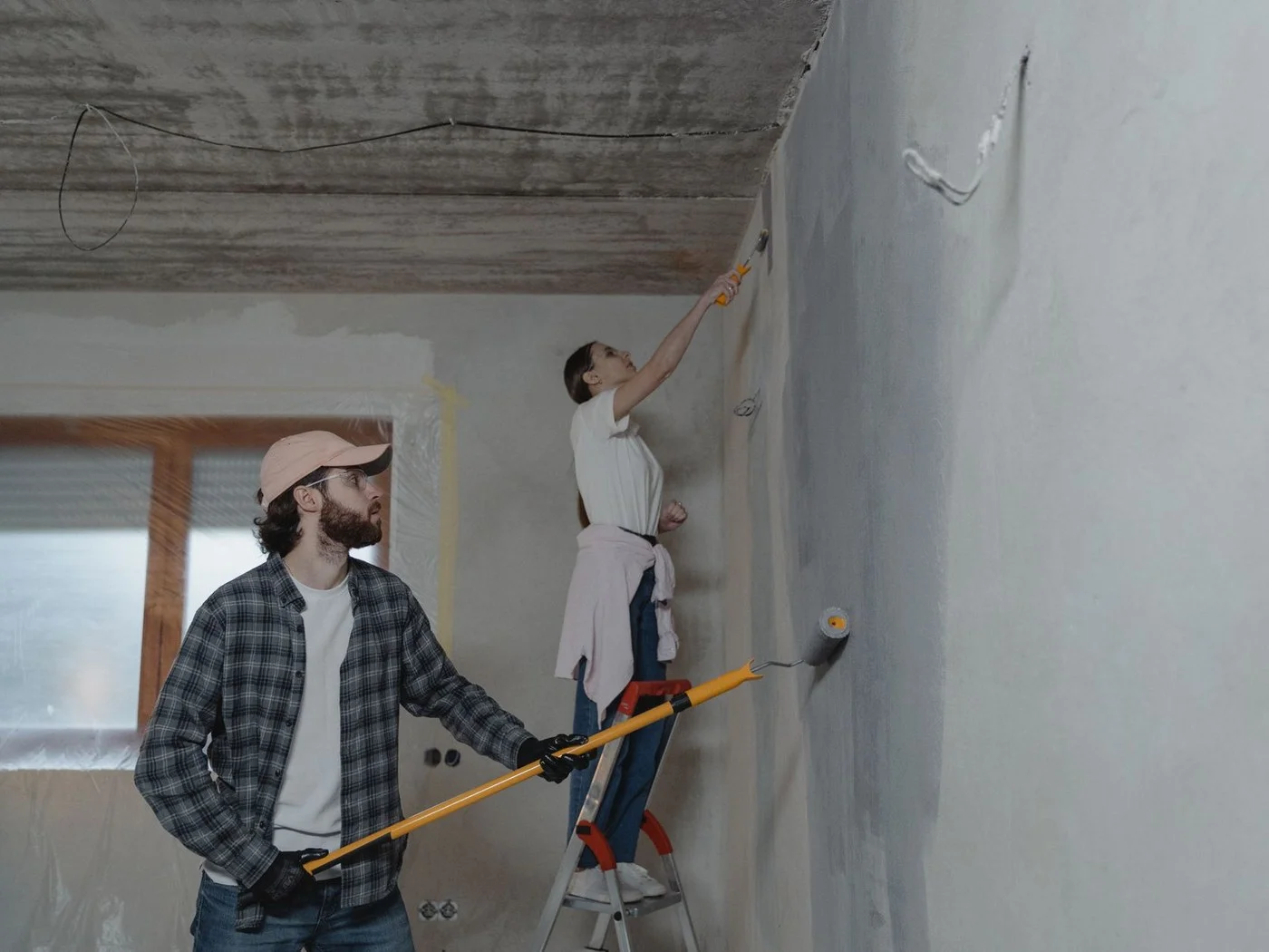 Couple repainting a room in a house that needs work