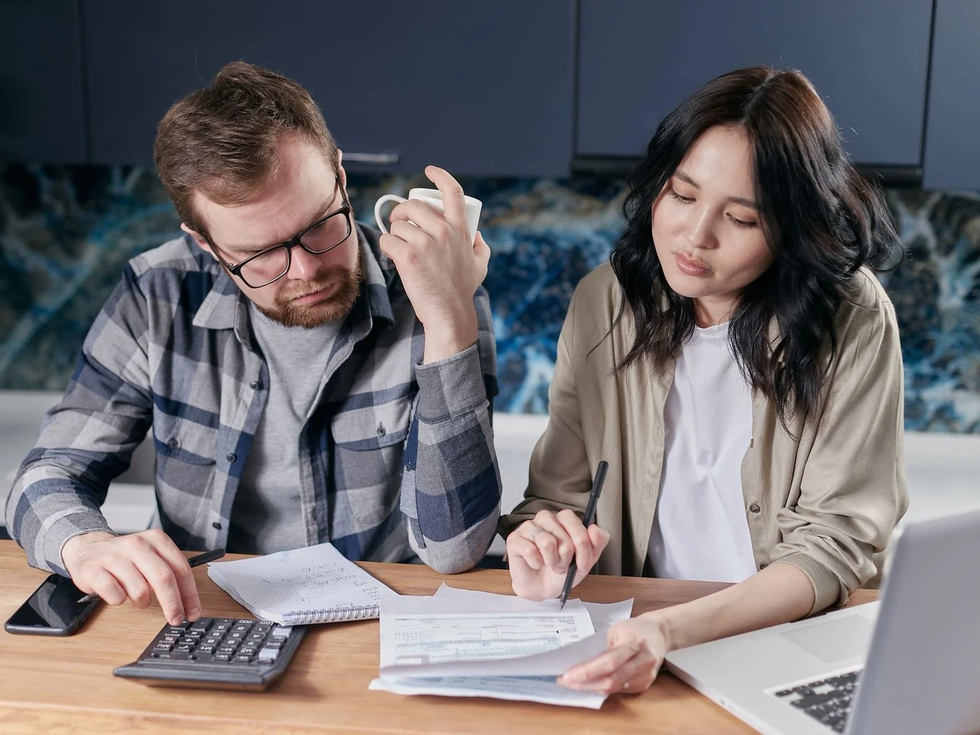 Couple going through bills with a calculator at the kitchen table