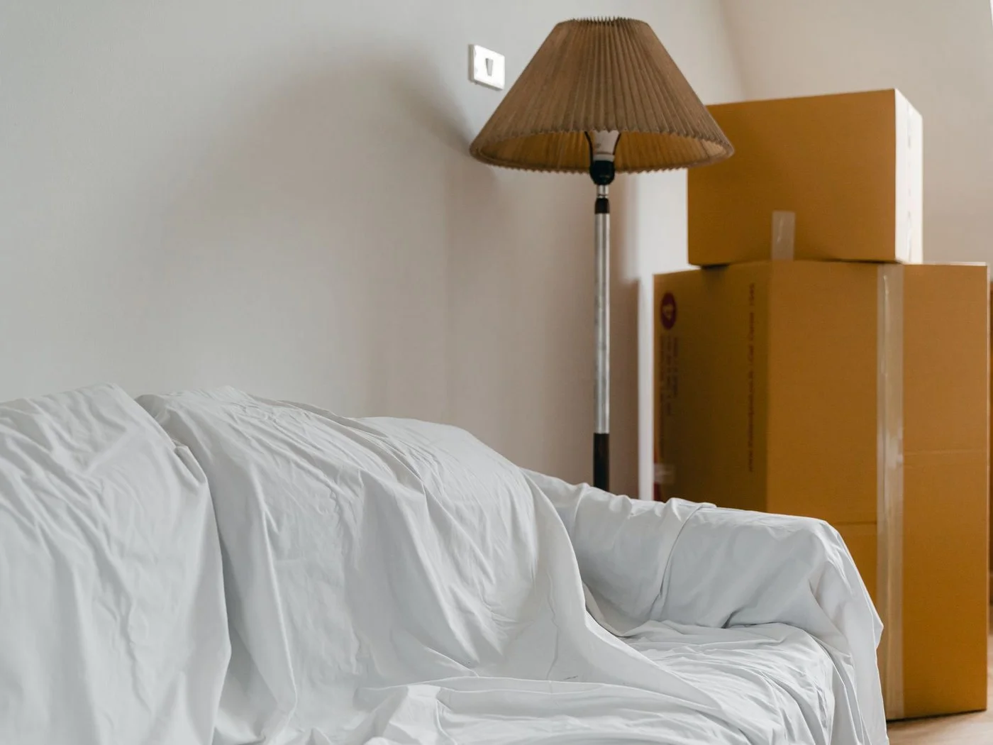 Furniture under white covers and packed boxes in an empty house